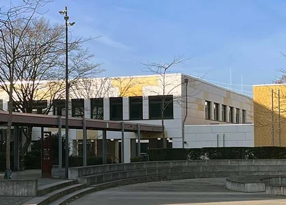 Schulhof mit modernen Gebäuden und Sitzstufen, Austragungsort des KMS-Ausbildungsforums in Krefeld.