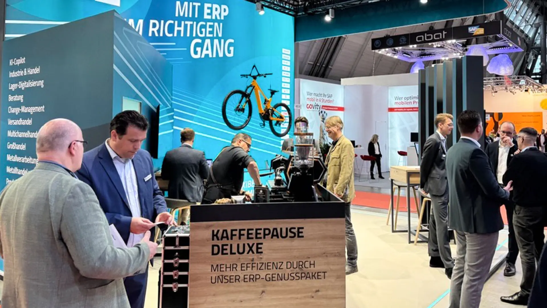 Messestand auf der LogiMAT Stuttgart 2025 mit ERP-Slogan, Kaffeebar und Gesprächen mit Besuchern