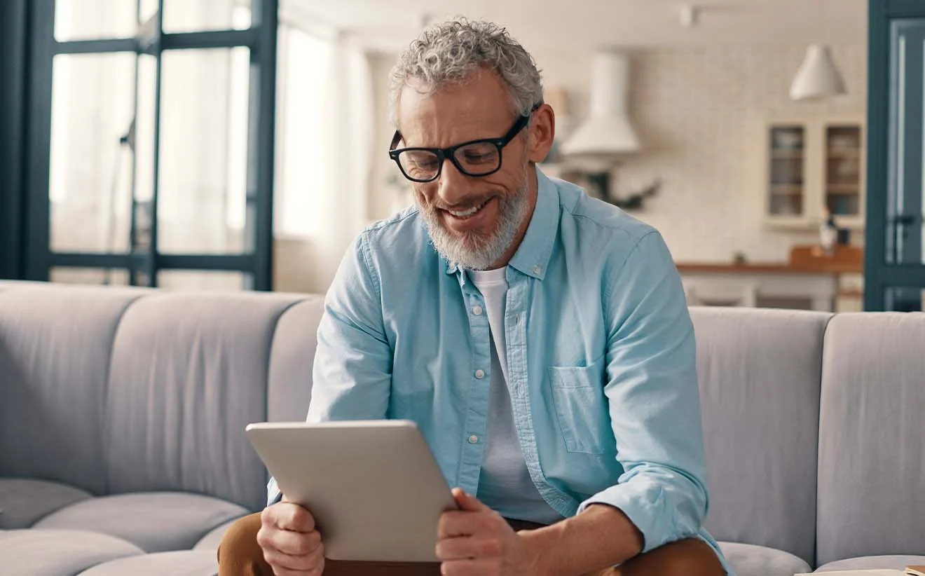 An aged man uses a solution for the pension benefits notification procedure on a tablet and smiles