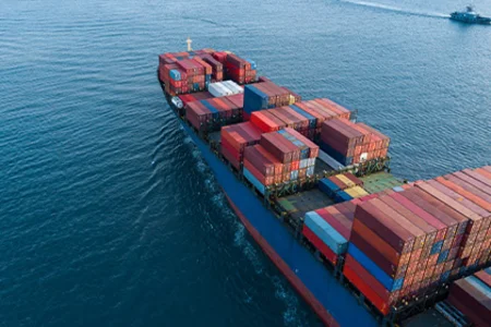 Containerschiff mit bunten Frachtcontainern auf offener See als Symbol für den technischen Handel.