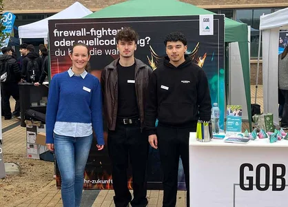 Ausbildungsmesse Moers 2025 am BCM – unser Team am GOB-Stand Drei Personen stehen am GOB-Messestand; hinten Plakate, vorne rechts Tisch mit Give-aways.