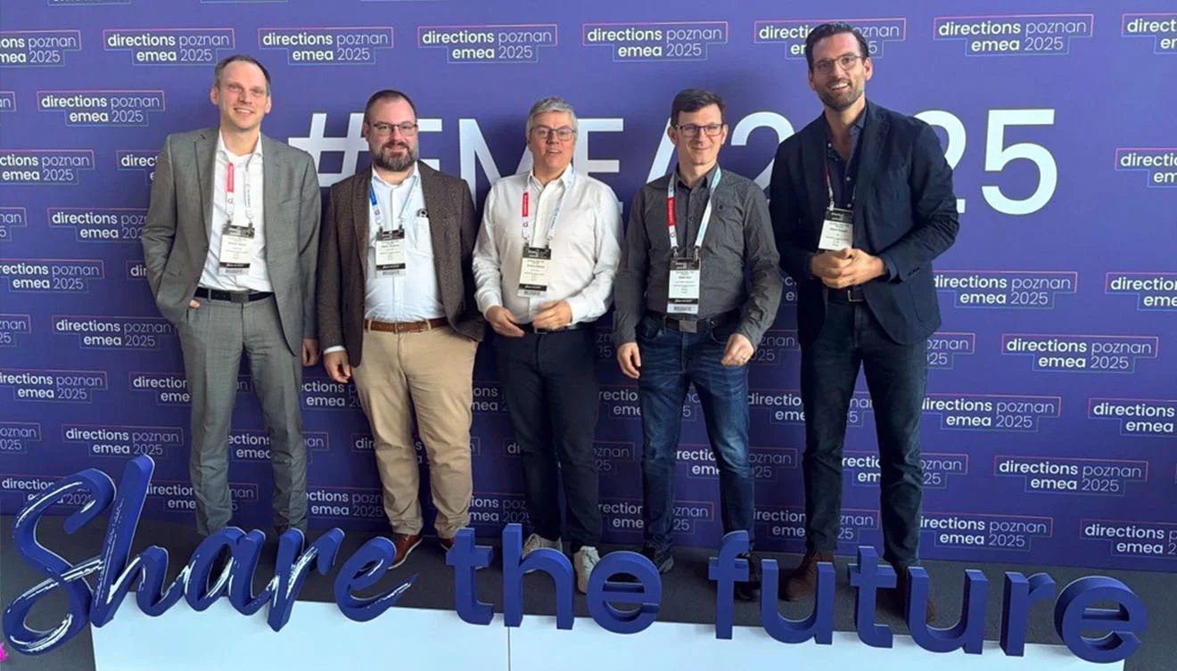 Directions EMEA 2025 in Posen – Share the future: unser Team vor Ort Fünf Personen vor der Directions EMEA 2025-Wand in Posen; Schriftzug „Share the future“.