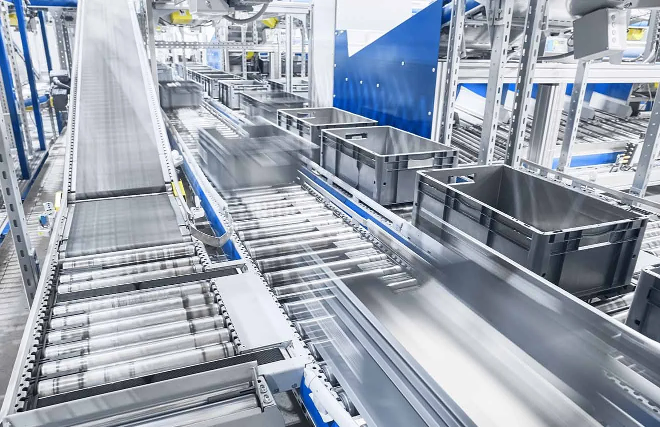 Conveyor system with roller tracks and grey containers for fast material flow in series production.