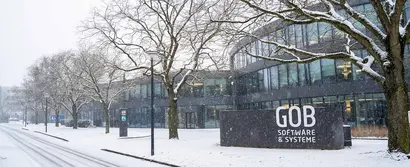 GOB-Gebäude im Winter, umgeben von schneebedeckten Bäumen und Straßen.