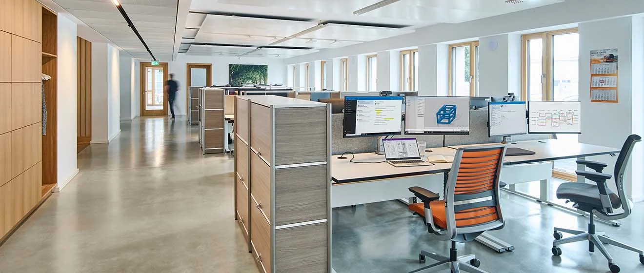 Großzügiges Open-Space-Büro beim ACV in Köln mit Arbeitsplätzen, Monitoren und Tageslichtfenstern.