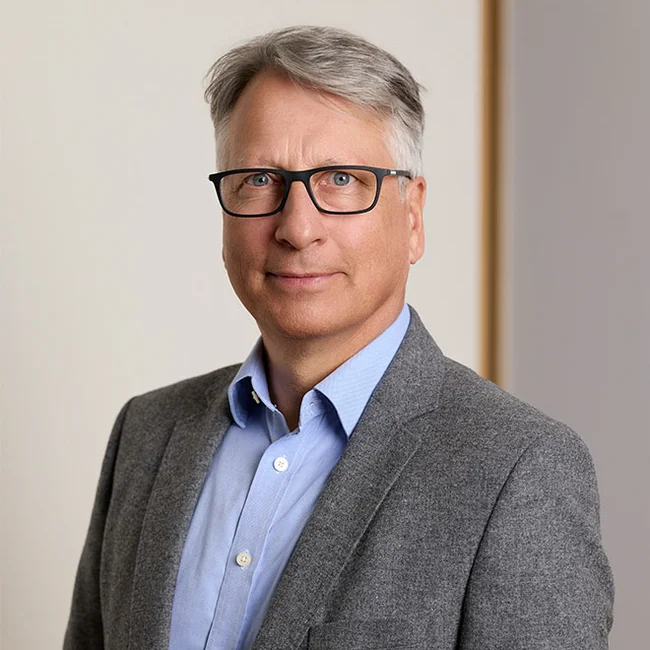 Holger Küster – Geschäftsführer vom ACV Porträt eines Mannes mit Brille im grauen Sakko vor hellem Hintergrund.