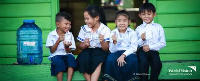 Echtstart bei World Vision Deutschland e. V. | unitop Fundraising Vier lachende Kinder auf grüner Holztreppe mit Wasser in der Hand, links ein Wasserbehälter.