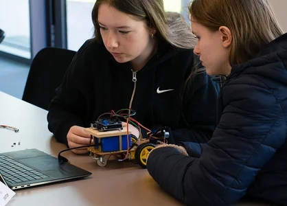 Girls’Day 2025: Programmierung von Arduino-Roboter | 1920 x 780 Pixel Zwei Teilnehmerinnen des Girls'Day 2025 programmieren einen Arduino-Roboter gemeinsam am Laptop.