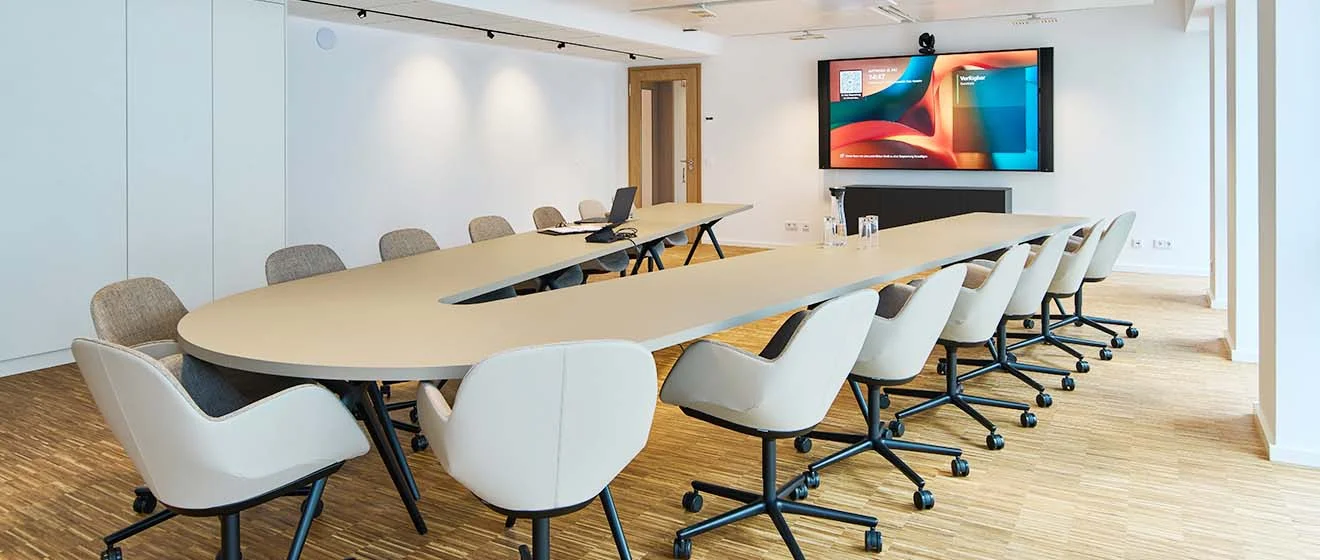 Moderner Konferenzraum mit U-förmigem Tisch, Stühlen und großer Bildschirmwand beim ACV in Köln.