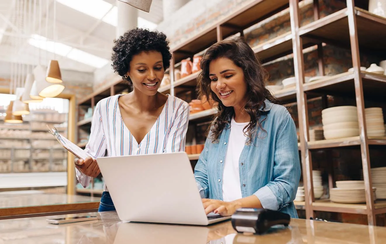 Two employees are looking at a laptop together at the shop counter.