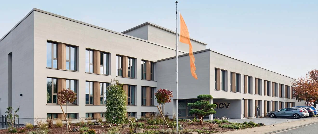 ACV-Hauptsitz in Köln, mit moderner Fassade, Flagge und Parkplatz im Eingangsbereich