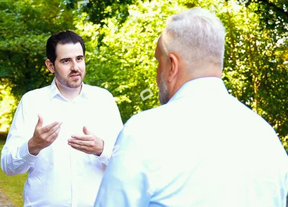 Walk & Talk | unitop BI | Experteninterview | 1905 x 425 Pixel Zwei Männer im Gespräch bei „Walk and Talk“-Format im Grünen, rechte Bildhälfte mit Porträtaufnahme