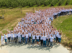 Team GOB in weißen T-Shirts versammelt in grüner Landschaft und fröhlich in die Kamera winkend